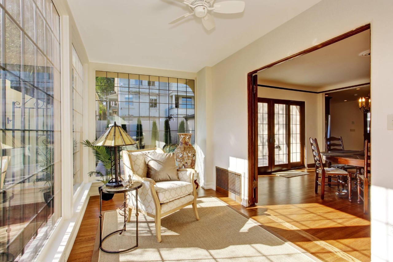 A bright sunroom with large, grid windows, white walls, and an antique chair at Blind King near Providence, RI